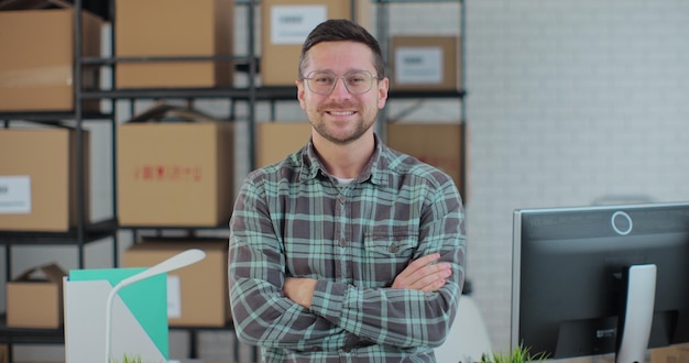 Portrait of attractive man looking at camera with arms crossed The owner of a successful business works in a warehouse in an online store