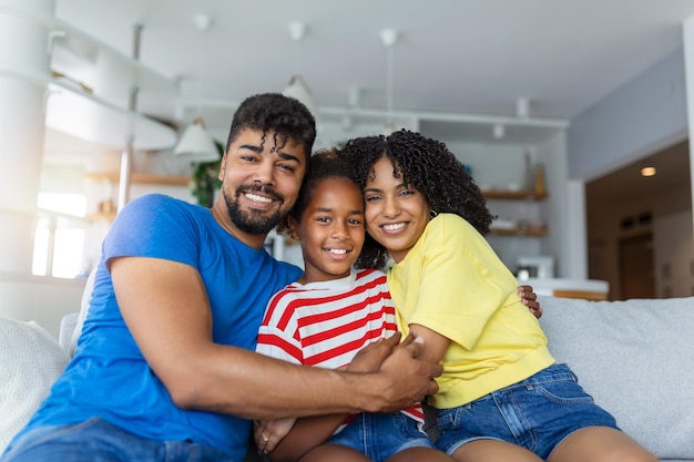 Portrait attractive multiethnic wife husband and kid indoors Close up married couple with little pretty daughter sitting together smiling looking at camera Concept friendly wellbeing happy family