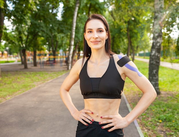 Portrait of attractive muscular brunette woman wearing black sports outfit, looking at camera