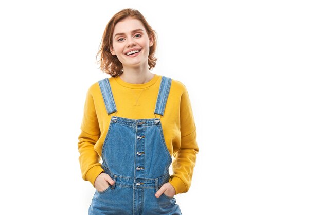 Portrait of attractive redhaired girl in yellow casual smiling joyfully isolated on white studio background