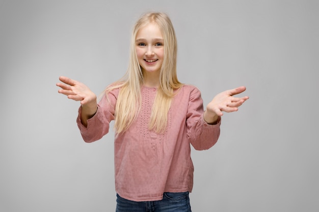 Photo portrait of attractive smiling sweet adorable blonde teenager girl in glasses in pink blouse with open arms