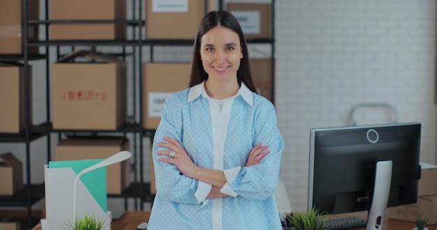 Portrait of an attractive woman looking at the camera crossing her arms The owner of a successful business works in a warehouse in an online store