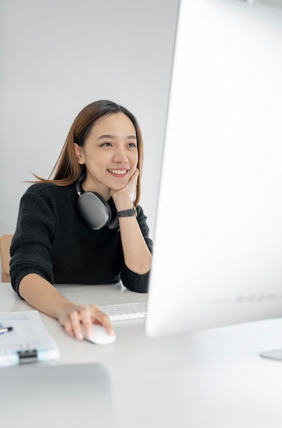 Portrait of attractive woman working on desktop computer sitting at her desk in modern office room Happy businesswoman working at office