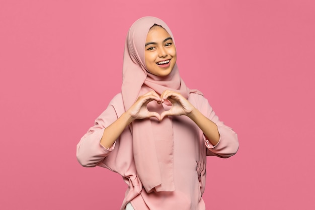 Portrait of attractive young Asian woman makes heart shape gesture with smiling face