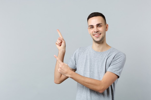 Portrait of attractive young man in casual clothes, pointing index fingers aside