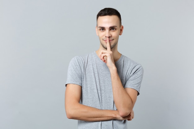 Portrait of attractive young man in casual clothes saying hush be quiet with finger on lips shhh gesture 