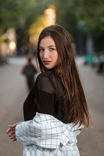 Portrait of an attractive young woman with long hair on park background Gaze of ravenhaired