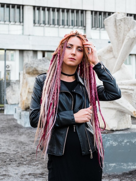 Portrait of attractive young woman with pink long de-dreadlocks in black clothes