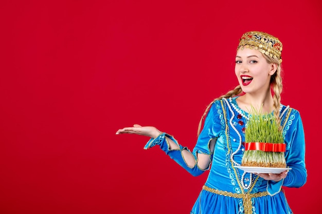 Portrait of azeri woman in traditional dress with green semeni on red background concept spring ethnic novruz