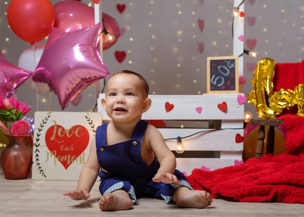 Portrait of a baby in a kissing booth decorated with hearts and balloons