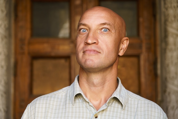 Portrait of bald man against the backdrop of building closeup model over  blue eyes and a light shir...