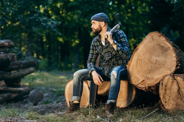 Portrait of a bearded brutal woodcutter holding ax in hand