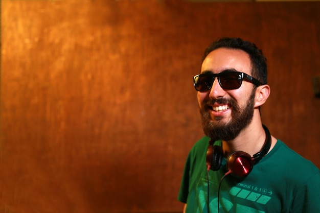 Portrait of a bearded disc jockey DJ with sunglasses and green shirt