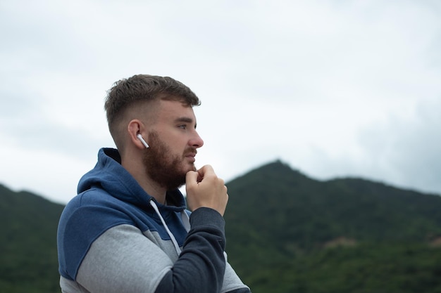 Portrait of bearded handsome pensive thoughtful guy listen music in earphones young upset sad