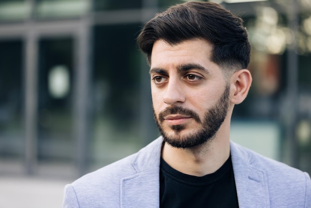 Portrait of bearded handsome young caucasian businessman standing look at camera serious outside