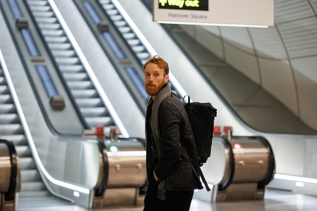 Portrait of bearded man tourist with backpack on background of escalators