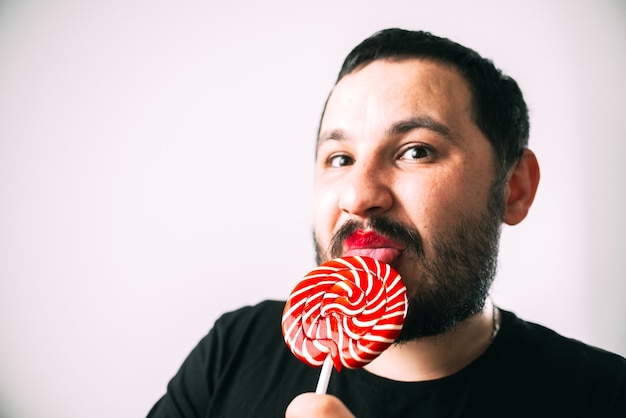 portrait of bearded man with glasses with round red Lollipop