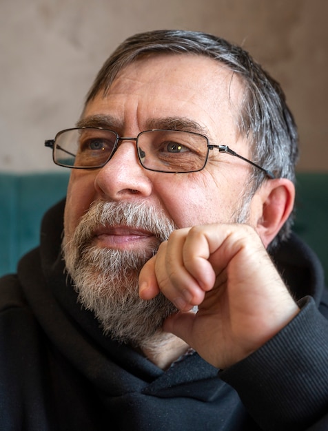 Portrait of bearded senior man in glasses indoors