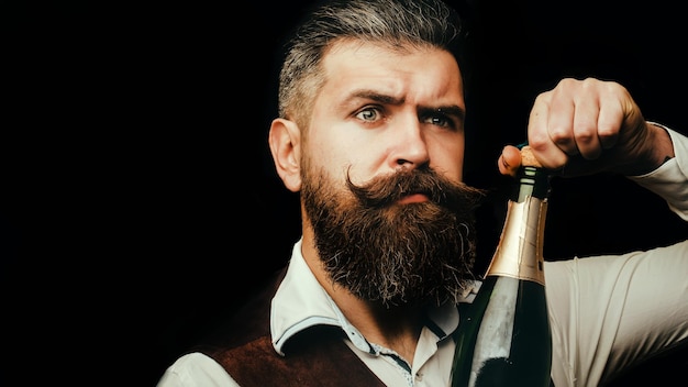 Portrait of a bearded waiter holding a champagne bottle close up portrait of man uncorking a bottle