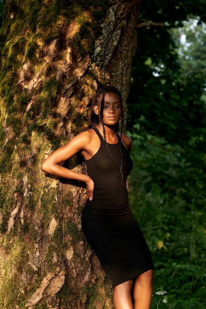 Portrait of beautiful african american woman standing in forest near trees