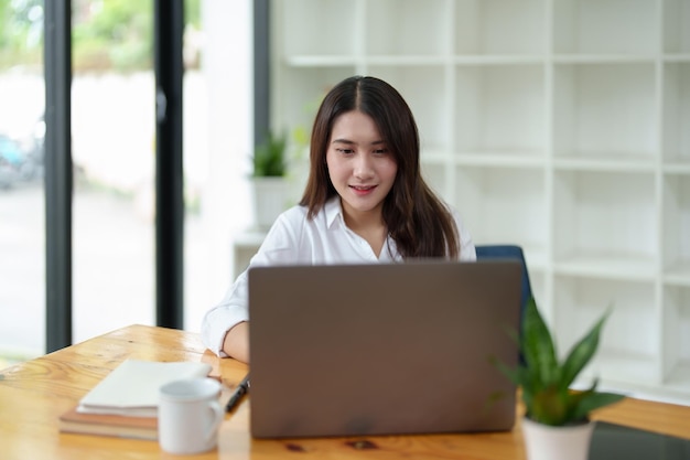 Portrait of a beautiful Asian businesswoman at work office desk with laptop computer in office