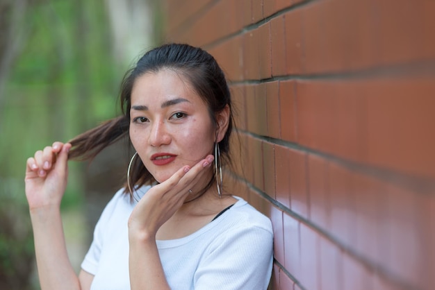 Portrait of beautiful asian chic girl pose for take a picture on brick wallLifestyle of teen thailand peopleModern woman happy concept