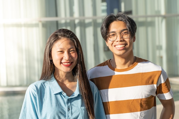 Portrait of a beautiful asian couple smiling outdoors in the student campus during a sunny day