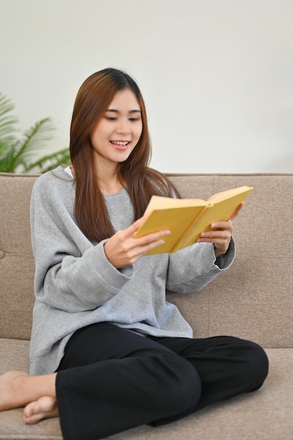 Portrait Beautiful Asian female sits on her sofa reading a book