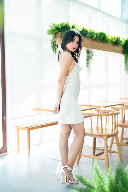 Portrait beautiful asian freelance Success people business woman fashion model in summer white sleeveless dress and coffee in cup in coffee shop