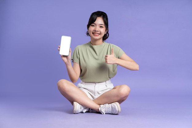 Portrait of beautiful asian girl sitting on purple background