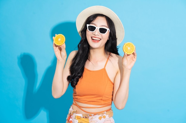 Portrait of a beautiful asian girl in a swimsuit smiling happily on a blue background