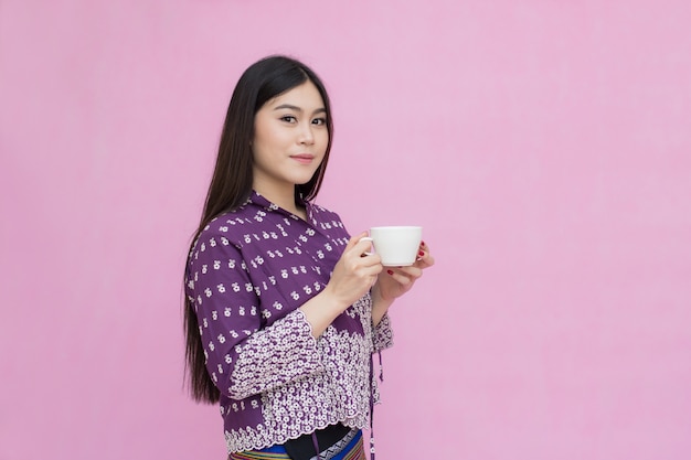 Portrait beautiful Asian girl in traditional Thai dress and holding coffee cup 