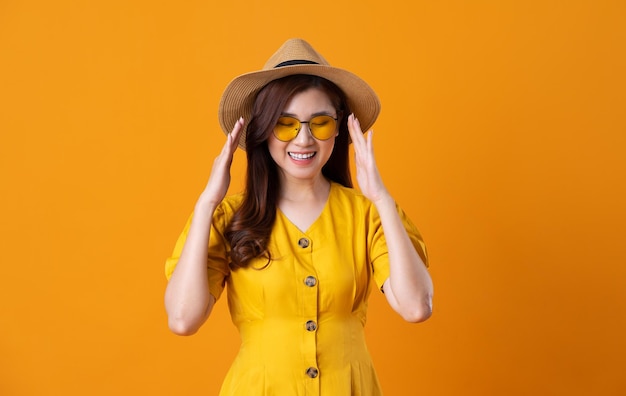 Portrait of beautiful asian girl wearing yellow dress on orange background