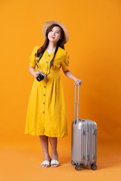 Portrait of beautiful asian girl wearing yellow dress on orange background