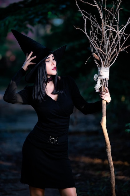 Photo portrait of beautiful asian sexy woman wear black witch costume with broomhalloween festival concept