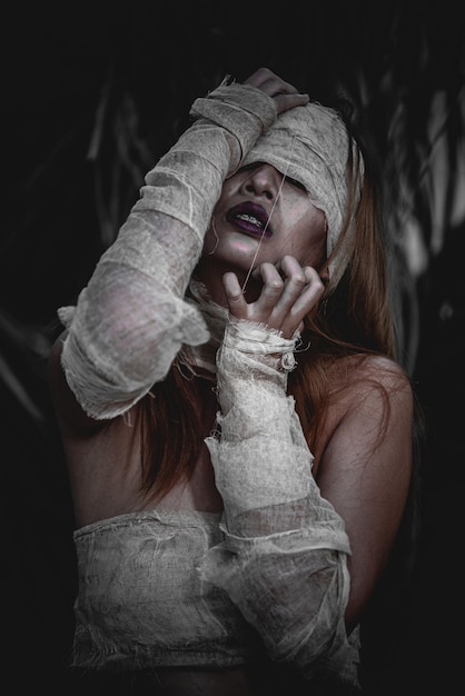 Photo portrait of beautiful asian sexy woman wear mummy costume in the foresthorror movie scenehalloween poster