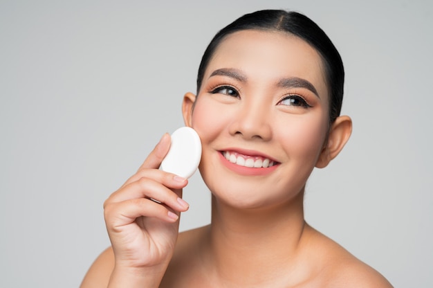 Portrait of Beautiful Asian woman holding foundation or cushion sponge puff