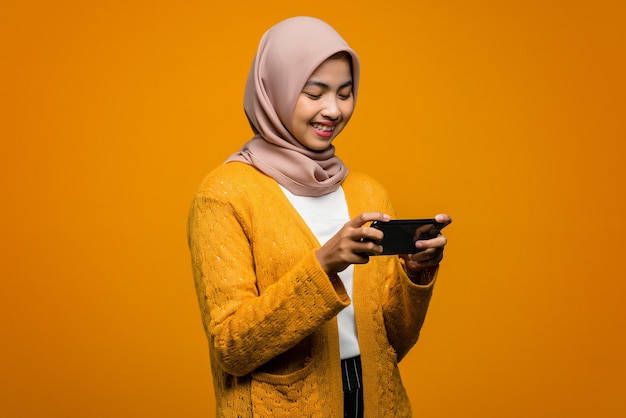 Portrait of beautiful Asian woman playing a video game on a smartphone with happiness expression