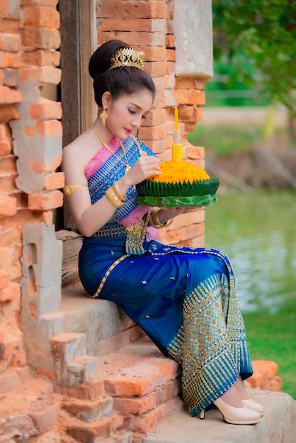 Portrait of beautiful asian woman in Thai dress traditional praying hold kratong for join loy kratong festival at thailand