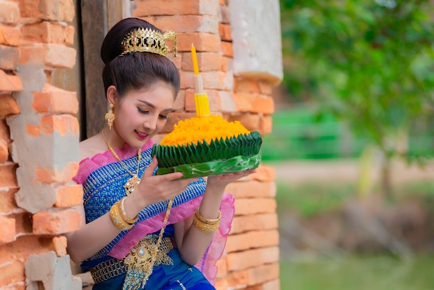 Portrait of beautiful asian woman in Thai dress traditional praying hold kratong for join loy kratong festival at thailand