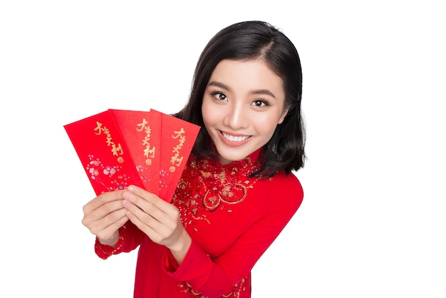 Portrait of a beautiful Asian woman on traditional festival costume Ao Dai holding red pocket - lucky money. Tet holiday. Lunar New Year. Text mean Happiness and Happy