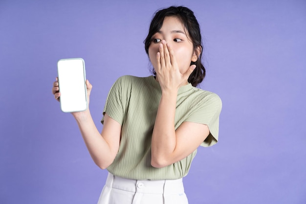 Portrait of beautiful asian woman using smartphone on purple background