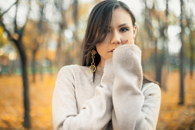 Portrait of a beautiful asian woman walking outdoors Beautiful woman in a sweater Fashion portrait of stylish beautiful woman outdoors