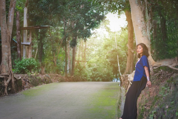 Portrait of beautiful Asian woman with local dress, standing under big tree beside the road at count