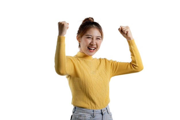 Portrait of a beautiful Asian woman in a yellow shirt standing with her hands up in joy portrait concept used for advertisement and signage isolated over the blank background copy space