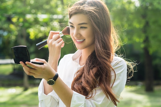 Portrait of beautiful asian young woman make up to her face in the park,