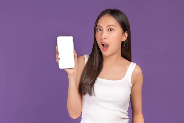 Portrait of beautiful Asian young woman showing smart phone with blank screen white screen empty copy space for advertising banner isolated on purple background Mock Up Image