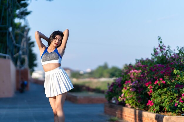 Portrait of beautiful athletic young asian woman in fashionable sportswear standing and having rest after strong exercise training in garden the parkOutdoor Sporty concept