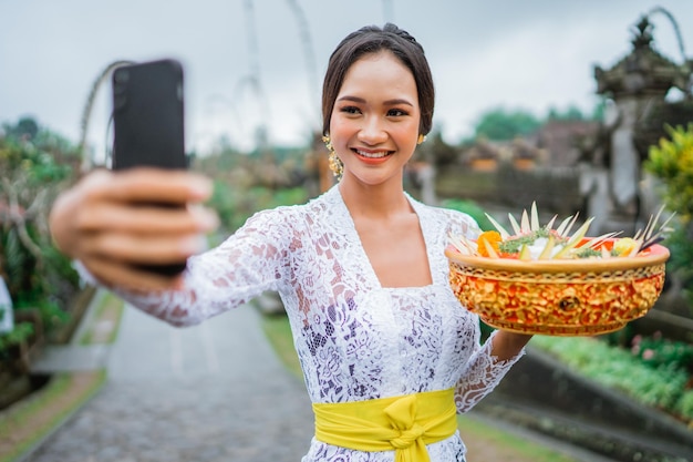 Portrait of beautiful balinese woman wearing kebaya taking self portrait