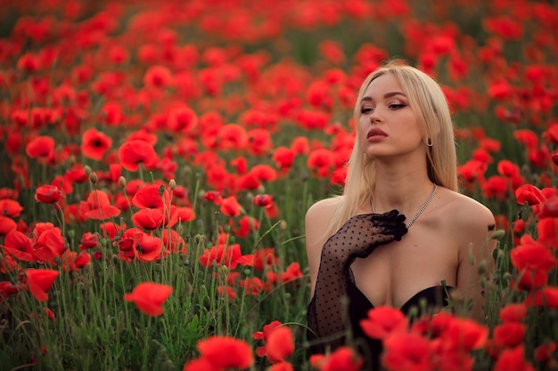 Portrait of a beautiful blonde woman in a straw hat at sunset on a poppy field